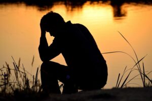 depressed, emotionally immature man sitting by a lake