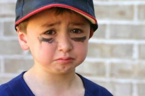 little boy in baseball cap with look of sadness and disappointment