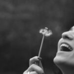 optimistic woman blowing dandelion