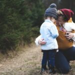 A mother shows good parenting skills as she kneels to talk to her child.