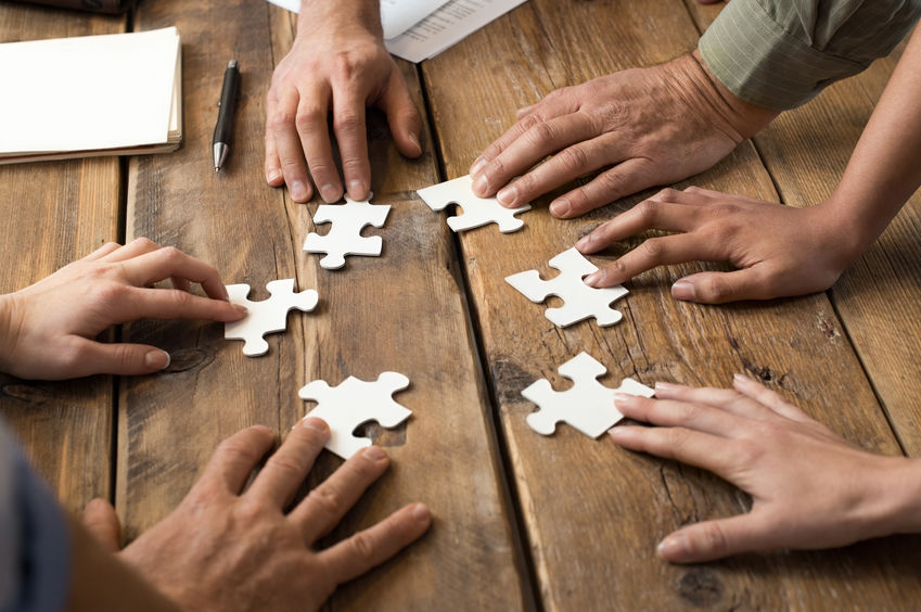 business men and women trying to solve a puzzle by collaborating