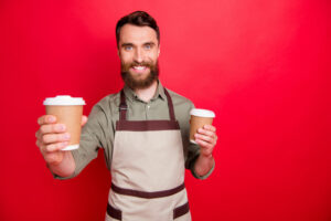 close up of man offering a cup of latte to a friend.