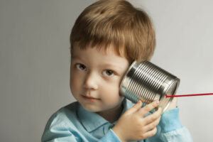 small boy listening through tin can