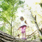 Young girl standing on a log, facing her fear
