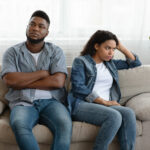couple seated on couch using poor listening skills