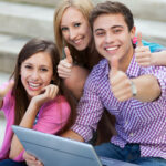 Friends with laptop giving a thumbs up