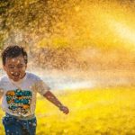 happiness of a little boy playing in sprinklers